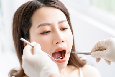 the asian woman is having a routine dental exam at the dental clinic