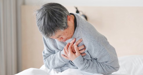 asian elderly man wake up on bed and he has heart attack in the morning