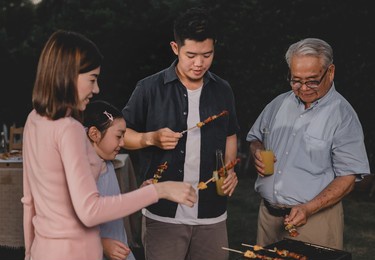 asian family having a barbecue party at home. cooking grilled bbq for dinner in backyard. lifestyle on summer holiday.