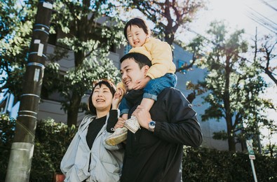 happy japanese family spending time outdoor. mom, dad, and daughter walking and having fun in tokyo.