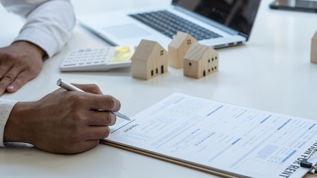 young man hand holding a pen, contract, insurance concept, home insurance agent, small sample on the table demonstrating home protection for customers interested in insurance