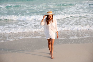 portrait image of a beautiful young asian woman strolling on the beach by the sea