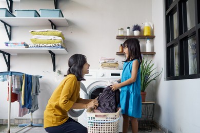 beautiful young asian woman and child girl little helper are doing laundry at home.