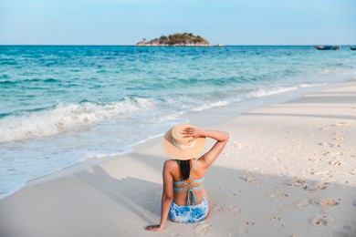 summer travel vacation concept, traveler asian woman with bikini and hat relax on sea beach at day in koh lipe, satun, thailand