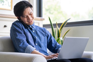 young asian man is calling while using computer
