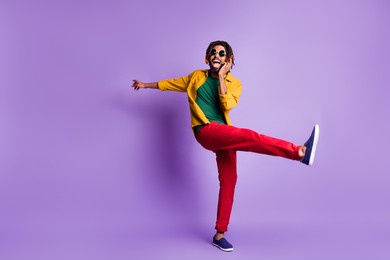 full body photo of positive dark skin person open mouth raise leg enjoy weekend isolated on violet color background
