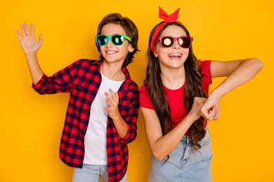 photo of two funky kids dance having fun wear sunglass casual clothes isolated yellow color background
