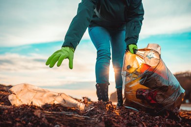 a volunteer collects garbage on a muddy beach. close-up. the concept of earth day. bottom view.