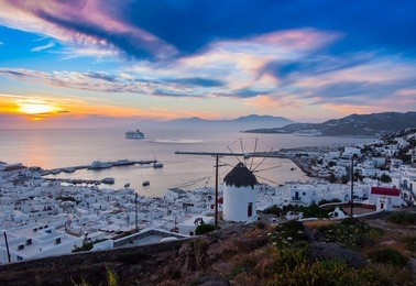 view of mykonos, windmill and old port with cruise ship at sunset