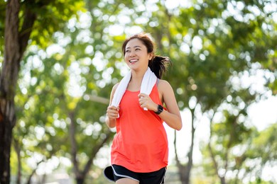 close up of beautiful asian runner running and smiling in the park in the morning.