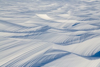 snow texture. wind sculpted patterns on snow surface. wind in the tundra and in the mountains on the surface of the snow sculpts patterns and ridges (sastrugi). arctic, polar region. winter background