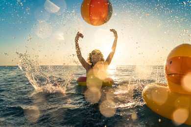 happy child having fun on summer vacation. kid playing with rubber duck and ball in the sea. healthy lifestyle concept. spring break!