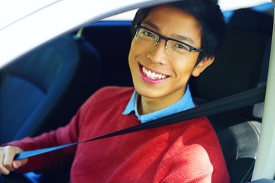 young asian man fastening seat belt