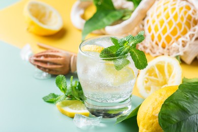 hard seltzer cocktail with lemon, mint and ice on a table. summer refreshing beverage, drink with trendy zero waste accessories, bamboo straw and mesh bag.
