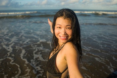 beautiful asian woman enjoying beach holidays - young happy and attractive korean girl in bikini posing playful at tropical beach during summer vacation in travel concept