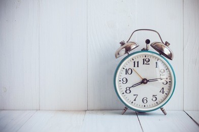 big old vintage alarm clock with bells, painted white wooden background
