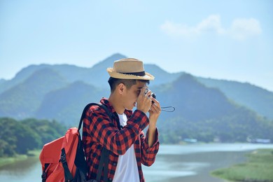 young asian travel photographer taking pictures outdoors