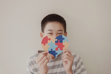 preteen boy holding puzzle jigsaw heart shape,  child mental health concept, world autism awareness day, teen autism spectrum disorder awareness concept