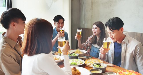 slow motion of group of asian happy friends drinking and toasting beer in restaurant
