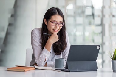 young asian businesswoman is happy to work at the modern office using a tablet.