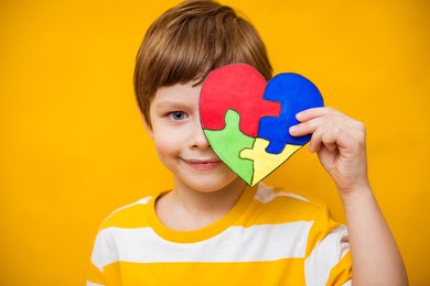 kid boy hands holding puzzle heart, child mental health concept, world autism awareness day, teen autism spectrum disorder awareness concept