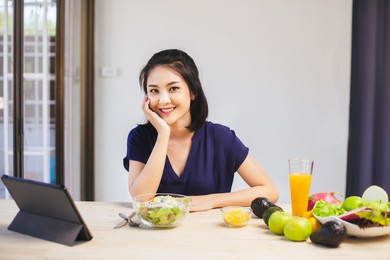 happy asian woman vegetarian healthy eating salad food and use tablet on the table. young woman vegetarian. vegetables and fruits. vegan food.