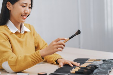 asian professional make-up artist working at beauty salon blending eyeshadow on face of a female client.