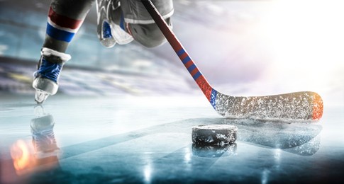 close up of ice hockey stick on ice rink in position to hit hockey puck.