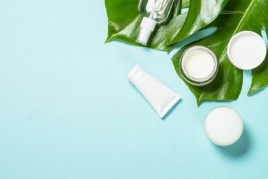 natural cosmetic products at blue background with green leaves. cream, mask, lotion for face and body care. top view image with copy space.