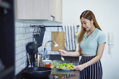 young asian teenage female prepare vegetable and cocking food at kitchen at apartment