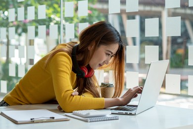 portraits of beautiful smiling asian women relax using laptop computer technology while sitting on their desks and using their creativity to work, work from home concept.