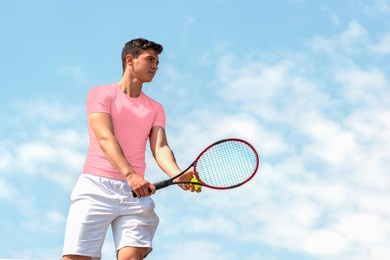 young handsome tennis player with racket and ball prepares to serve at beginning of game or match. beautiful colorful sports background, banner with copy space