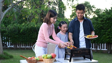 asian family having a barbecue party at home. cooking grilled bbq for dinner in backyard. lifestyle on summer holiday.