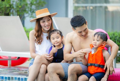 young asian family relaxing in swimming pool. family on vacation having fun by pool, happiness lifestyle concepts