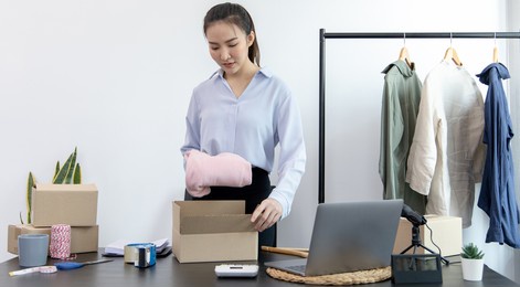 young asian women pack their clothes into boxes and prepare them to be delivered by post, online clothing sales business, business of selling clothes on social media or selling online.