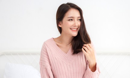 smiling of cheerful beautiful pretty asian woman clean fresh healthy white skin posing in warm knitted pink clothes.girl felling relaxing and enjoy time on the bed at home.asia beauty