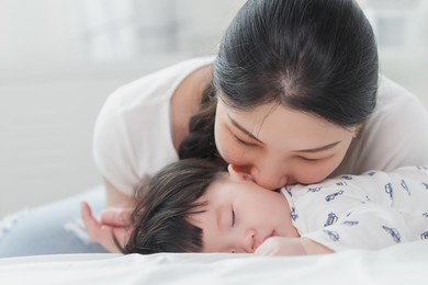 close up portrait of young beauty asian mother kissing her newborn baby boy while he sleep. healthcare and medical insurance. asia mother's day concept banner.