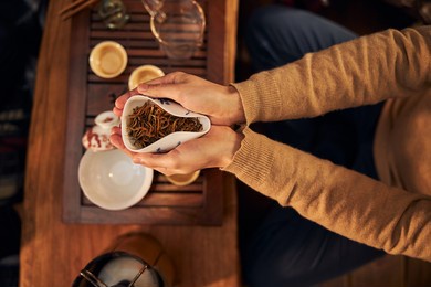 close up of young woman with tea leaves in her hands sitting at the table in cafe