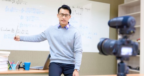 asian male professor teach calculus online through camera in classroom