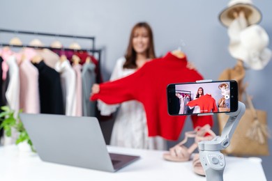 young woman selling clothes online by smartphone live streaming, business online e-commerce at home