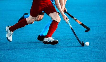close up of two field hockey players, challenging eachother for the control and posession of the ball during an intense, competitive match on professional level. vintage color filter