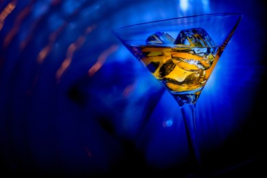 orange liqueur into a  glass. multicolored reflections on the background.