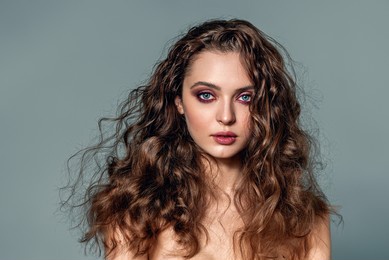 an attractive beautiful woman with natural curly shiny hair poses. a lot of hairstyle with the effect of beach curls.