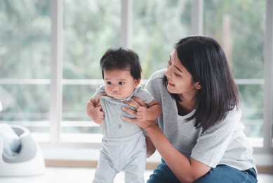 young beautiful asian mother playing with her baby.