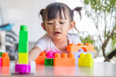 portrait image of 3-4 toddler kid. happy asian child girl playing the plastic block toys. learning and education concept. smiling little baby.