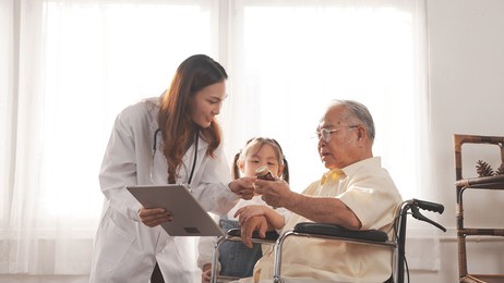 asian female nurse tells how to take medicine to elderly senior grandfather patient at home medical visit, elderly old male people healthcare support and encouraging the patient with granddaughter.