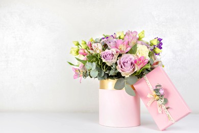 beautiful bouquet of flowers in round box and pink gift box on a white table. gift for holiday, birthday, wedding, mother's day, valentine's day, women's day. floral arrangement in a hat box.