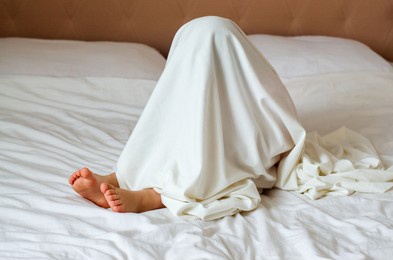 little child hiding under white blanket in bedroom. play therapy at home. toddler child playful, playing in bed. kids problems. childhood behavior problems. emotional disorder