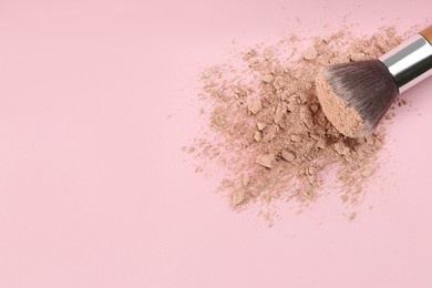 makeup brush and scattered face powder on pink background, top view. space for text