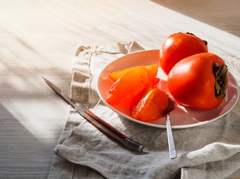 a plate of sliced persimmons on a gray wooden table by the window, shadows and sunlight fall on the persimmons.